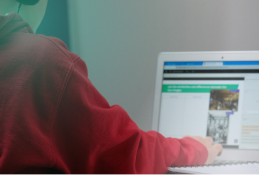 Young student in red hoodie using a laptop for online learning